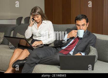 la coppia di età media a casa dal lavoro, ancora in formalware, avendo un caffè nel loro appartamento in città Foto Stock