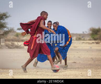 I giovani Masai Warriors giocano a calcio nella savana Foto Stock