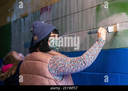 Il reverendo Jes Kast, pastore della Faith United Church of Christ in state College, aiuta a dipingere i graffiti supremacisti bianchi lasciati su un murale di orgoglio.dozzine di membri della comunità si sono riuniti a Jake's Cards and Games per ripagare il murale dell'orgoglio defaced dalla parte dell'azienda. I volontari hanno dipinto a turno i messaggi del gruppo nazionalista bianco Patriot Front. Foto Stock