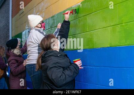 I membri della comunità riverniciano un murale che è stato sfidato dai graffiti nazionalisti bianchi.dozzine di membri della comunità si sono riuniti a Jake's Cards and Games per ripassare il murale dell'orgoglio defaced dalla parte dell'azienda. I volontari hanno dipinto a turno i messaggi del gruppo nazionalista bianco Patriot Front. Foto Stock