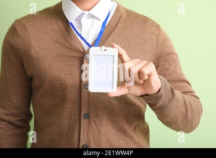 Giovane uomo con badge vuoto su sfondo a colori Foto Stock
