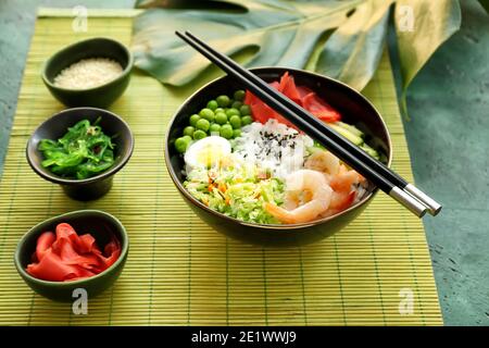 Ciotola con riso saporito, gamberi e verdure su sfondo colorato Foto Stock
