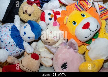 diversi tipi di peluche morbidi giocattoli sul pavimento ovunque in una camera per bambini Foto Stock