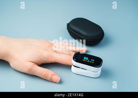 Misurazione del polso del livello di ossigeno con un ossimetro sulla mano di una persona. Foto Stock