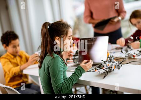 Smily African American insegnante di scienza femminile con gruppo di bambini programmazione di giocattoli e robot elettrici in classe robotica Foto Stock