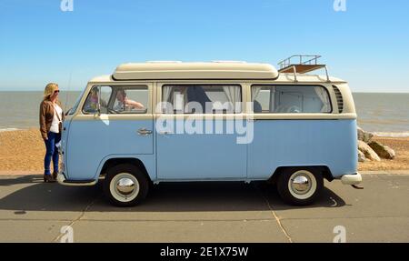 Un classico pulmino Volkswagen bianco e blu parcheggiato sul lungomare di Felixstowe con gli spettatori. Foto Stock