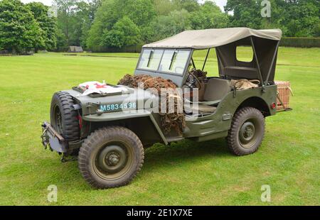 : Jeep della seconda Guerra Mondiale con bandiera della Croce Rossa parcheggiata su erba. Foto Stock