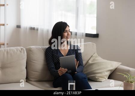 Felice giovane e sognante etnia asiatica bella donna con tablet digitale. Foto Stock