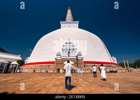 Uomo srilankano che cammina verso Ruwanwelisaya Stupa nel sacro Città di Anuradhapura nello Sri Lanka Foto Stock