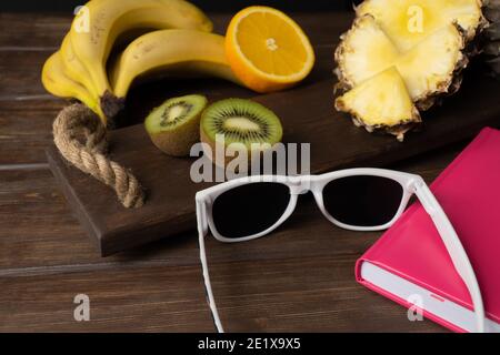 occhiali da sole e frutta sul tavolo. il concetto di una vacanza in paesi tropicali. frutta esotica in vacanza. umore estivo Foto Stock