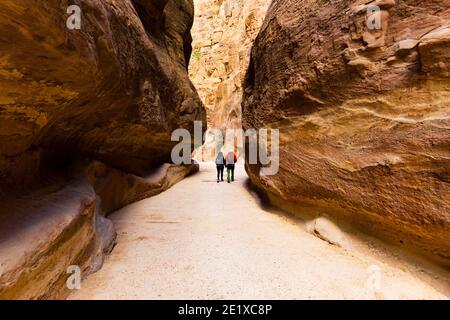 (Fuoco selettivo) vista mozzafiato di una coppia in lontananza camminando sul sentiero che conduce ad al Khazneh (il Tesoro). Foto Stock
