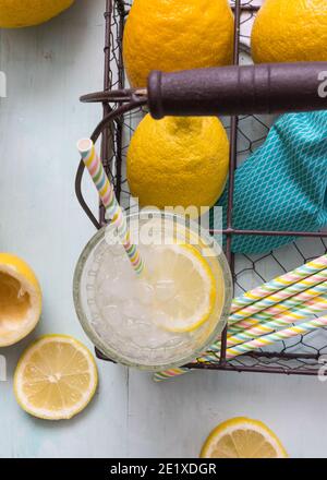 Bicchiere di limonata con una fetta di limone e una paglia all'interno. È collocato in un cestello metallico a sei fessure. Foto Stock