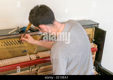 Processo di sintonizzazione del pianoforte. Primo piano della mano e strumenti di sintonizzazione che lavorano al pianoforte a coda. Vista dettagliata di piano verticale durante una sintonizzazione Foto Stock