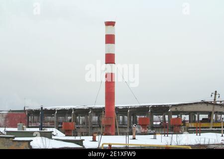 Zone industriali abbandonate contro il cielo grigio nuvoloso. Edifici distrutti con camini fumante sullo sfondo del paesaggio invernale del deserto. Foto di scorta WIT Foto Stock