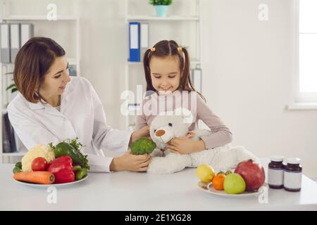 Nutrizionista giocando con la bambina e raccontandola dei benefici di mangiare cibo sano Foto Stock