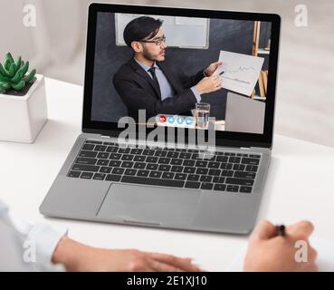 Primo piano dello schermo del portatile con l'uomo d'affari asiatico che fa la presentazione in linea Foto Stock