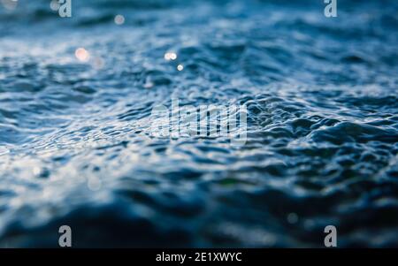 Onde sulla superficie dell'oceano. Consistenza d'acqua con bokeh e gocce Foto Stock