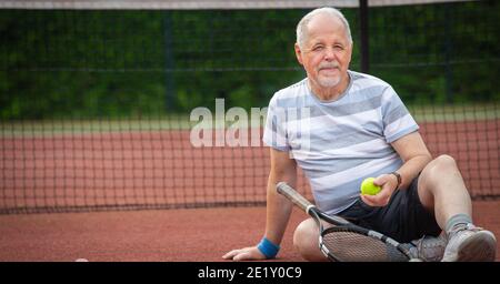 Ritratto di uomo anziano attivo che gioca a tennis all'esterno, in forma di pensionato Foto Stock