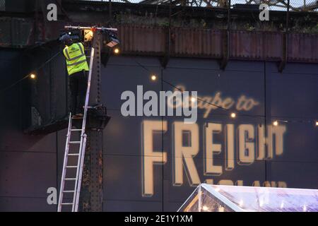 Un lavoratore fissa una luce a Escape to Freight Island. Foto Stock