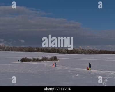 Burladingen, Germania - 01-09-2021: Splendido paesaggio invernale con campi innevati e persone che si divertano con le attività sportive invernali. Foto Stock