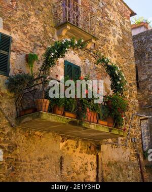 Un balcone in un palazzo storico in pietra nel villaggio di Montemerano vicino Manciano in provincia di Grosseto, Toscana, Italia Foto Stock