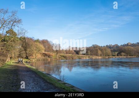 Persone che camminano sul lato di un lago ghiacciato a Hardwick Hall, Debyshire. Foto Stock
