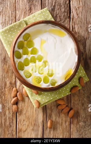 L'ajollanco è una popolare zuppa spagnola fredda fatta di pane, mandorle tritate, aglio, acqua, olio d'oliva chiodo di garofano nel piatto sul tavolo. Vie. Verticale superiore Foto Stock