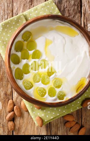 L'Ajo blanco è una deliziosa zuppa di mandorle fredde e aglio tipica dello spicchio della Spagna meridionale nel piatto. Vista dall'alto verticale Foto Stock