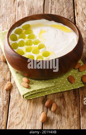 L'ajollanco è una popolare zuppa spagnola fredda fatta di pane, mandorle tritate, aglio, acqua, olio d'oliva chiodo di garofano nel piatto sul tavolo. Verticale Foto Stock