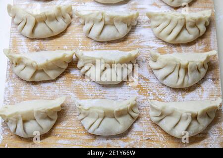 Gyoza crudo. Pronto per la cottura. Versione giapponese di gnocchi. Profondità di campo poco profonda. Foto Stock