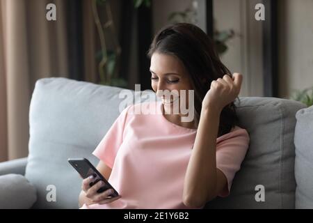 Esaltata donna etnica trionfa con messaggio sul cellulare Foto Stock