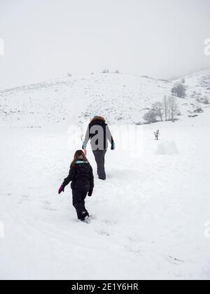 Due persone che camminano attraverso la neve Foto Stock