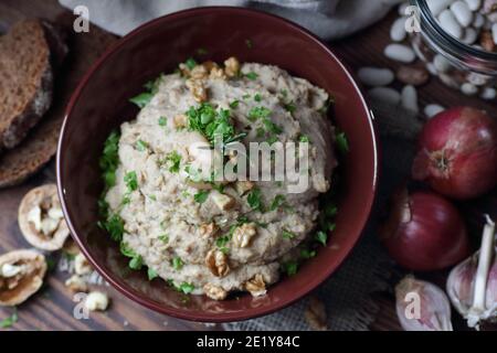 Pasta di fagioli o antipasto con noce e cipolla fritta in una ciotola su tessuto di lino su sfondo nero scuro moody, closeup, copy space, vegan e l Foto Stock