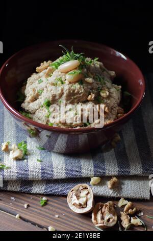 Pasta di fagioli o antipasto con noce e cipolla fritta in una ciotola su tessuto di lino su sfondo nero scuro moody, closeup, copy space, vegan e l Foto Stock