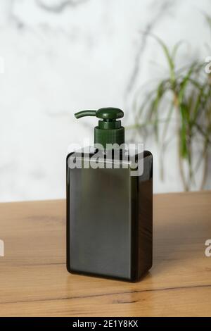 Verde pompa vuota bottiglia cosmetica mockup senza etichetta sul tavolo in bagno. Confezione dispenser shampoo di lusso. Foto Stock