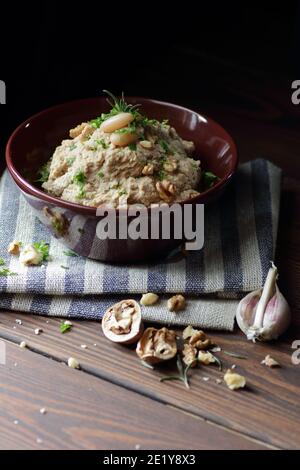 Pasta di fagioli o antipasto con noce e cipolla fritta in una ciotola su tessuto di lino su sfondo nero scuro moody, closeup, copy space, vegan e l Foto Stock