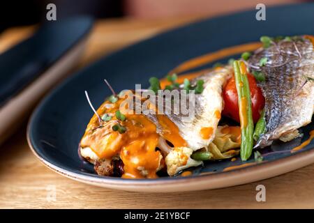 Cibo di mare. Dorada al forno con verdure in salsa di gamberi sul tavolo, serve in un ristorante, menu concetto di cibo Foto Stock