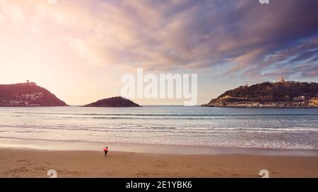 2020 02, Donostia, Spagna. Surfer che lascia la spiaggia di Concha in inverno. Foto Stock