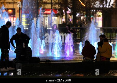 Le persone si siedono intorno alle fontane dei Piccadilly Gardens di Manchester. Foto Stock