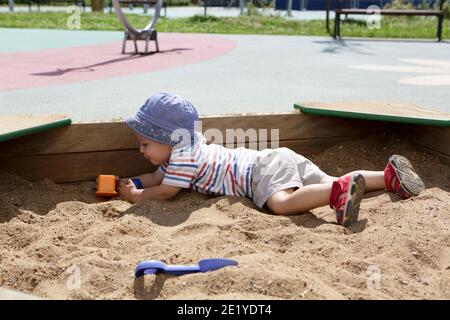 Capretto in cappello di panama che strisciano in sandbox Foto Stock