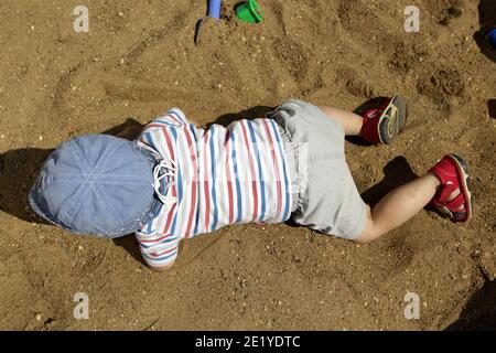 Ragazzo a panama cappello strisciando in sandbox Foto Stock