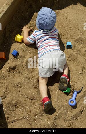 Bambino a panama cappello strisciando in sandbox Foto Stock