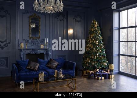 Ampio soggiorno con finestre panoramiche e pareti blu. Decorazioni di Natale in sala. Albero di natale Foto Stock