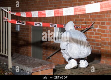 Amburgo, Germania. 10 gennaio 2021. Un dipendente del dipartimento di medicina legale si trova all'ingresso del seminterrato di un edificio di appartamenti nel quartiere di Neuallermöhe. Domenica una donna è stata uccisa in un violento attacco in casa. Credit: Daniel Bockwoldt/dpa/Alamy Live News Foto Stock