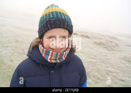 Un ritratto di un ragazzo sorridente all'aperto in inverno Foto Stock