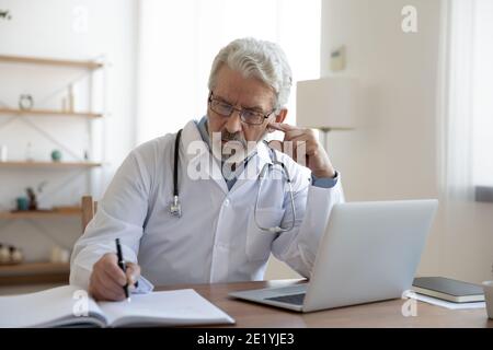 Focalizzato serio medico di mezza età che lavora in clinica. Foto Stock