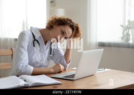 Giovane donna stressata medico generale che guarda lo schermo del portatile. Foto Stock