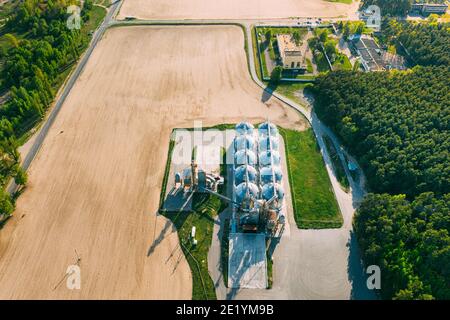 Vista aerea Granaio moderno, complesso di essiccazione cereali, cereali commerciali o silos semi nel paesaggio rurale della sorgente solare. Essiccatoio per mais Silos, cereali interni Foto Stock