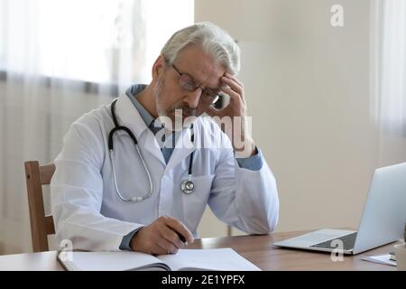 Stressato medico di mezza età che lavora in clinica. Foto Stock