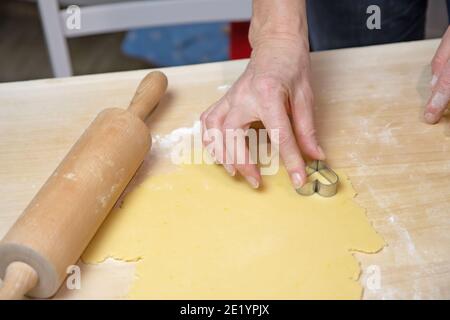 Tagliare i biscotti fatti in casa a forma di piccolo cuore come una sorpresa per San Valentino. Foto Stock